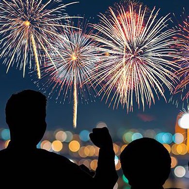 A silhouette of two people watching fireworks in the distance