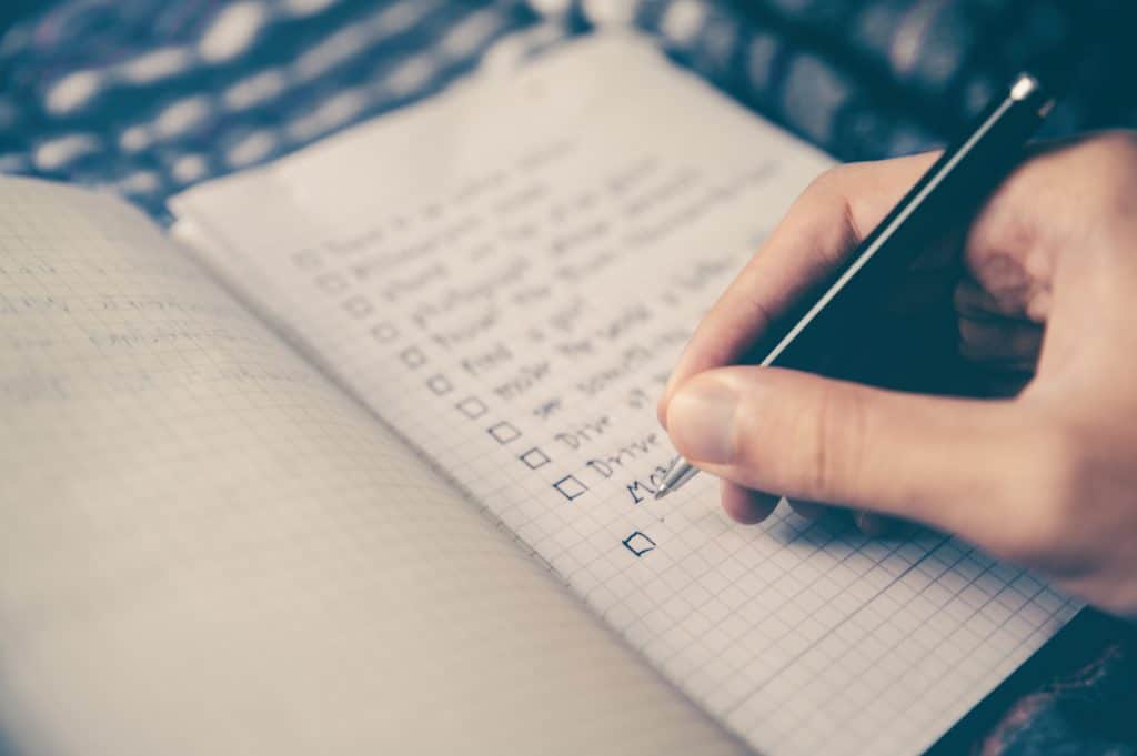 A photo of a hand writing a checklist in a journal