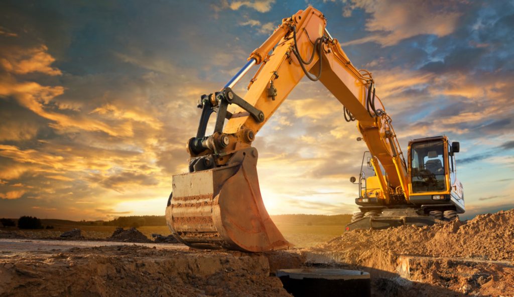 A stock photo of a large piece of digging equipment with a sunrise behind it.