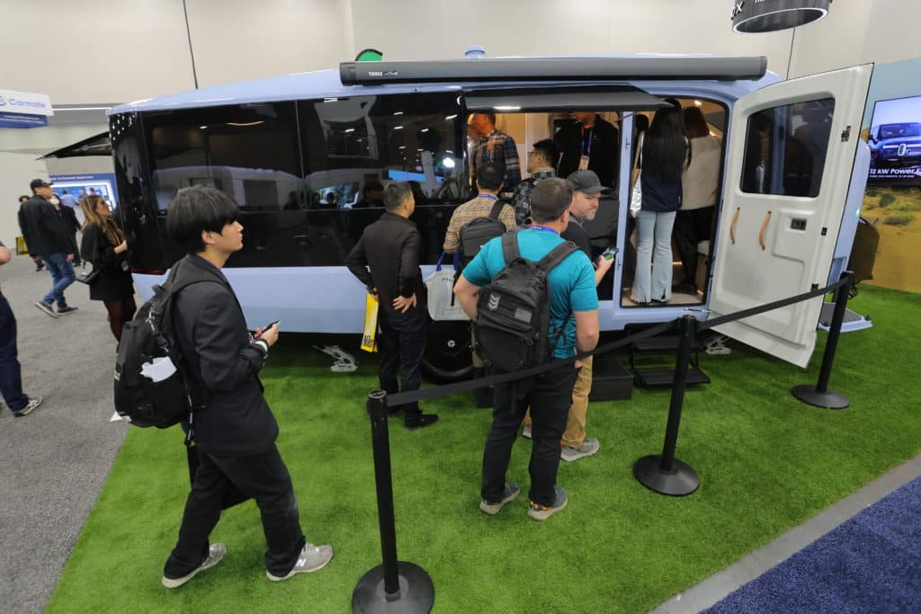 Attendees exploring the Pebble Flow all-electric camper trailer at CES 2025, showcasing its sleek and futuristic design.