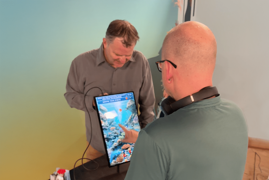 An engineer from Denver-based 303 Software tests a custom educational game on a touchscreen app on a vertical display.